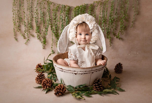 Baby girl in a lace romper posing with a white bunny