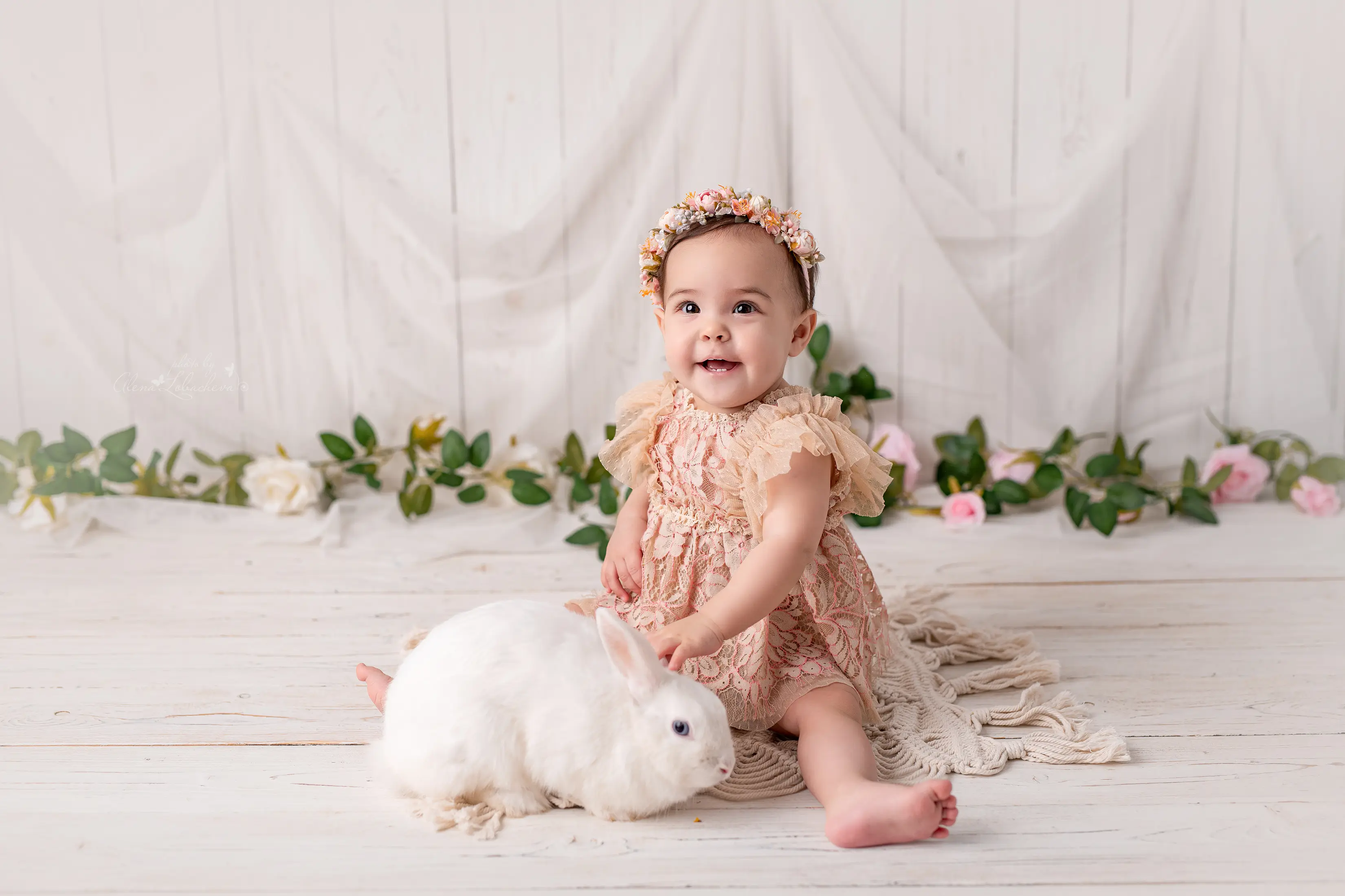 Baby girl in a soft lace romper posing with a white bunny