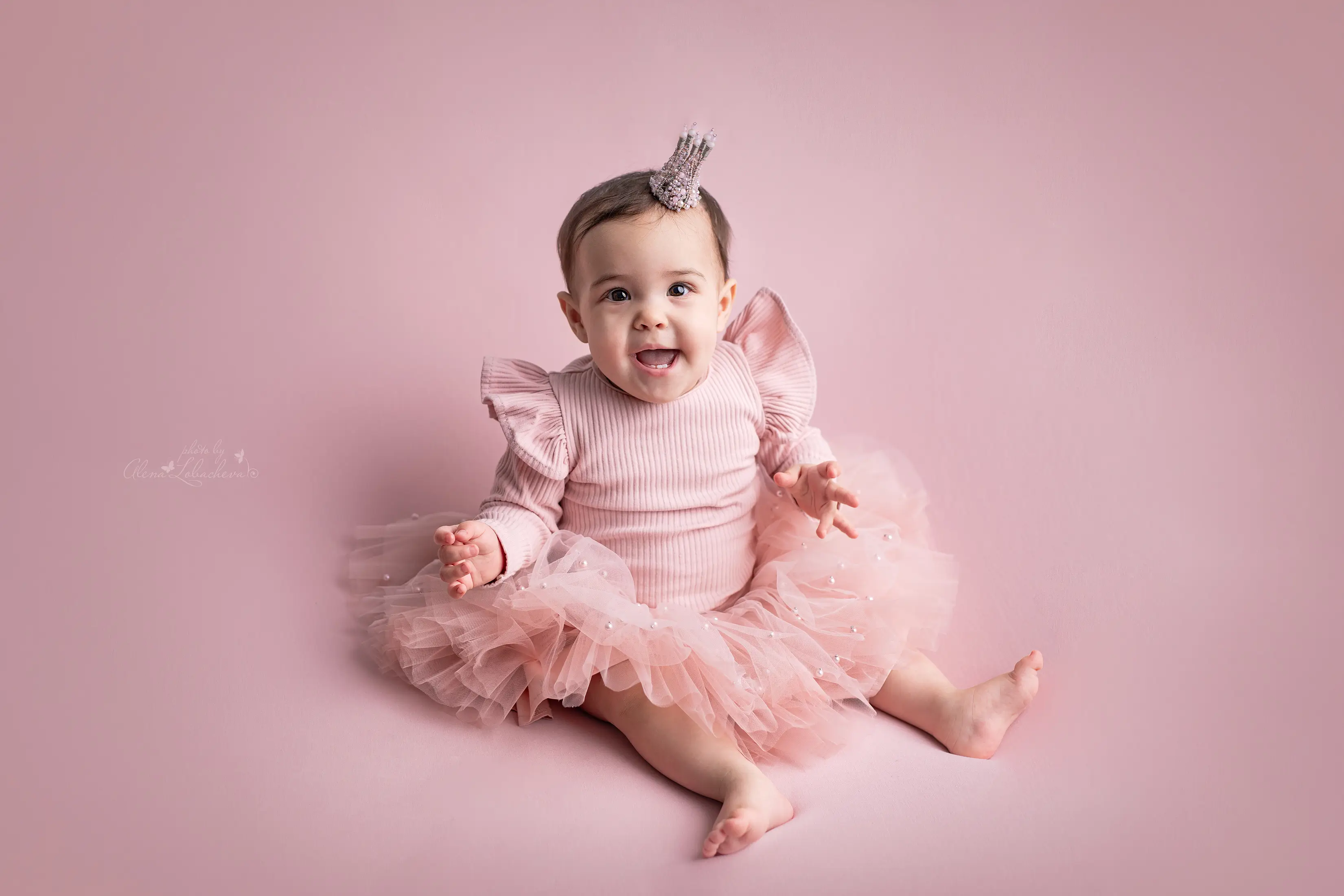 Baby girl sitting in a pink princess dress during a milestone session