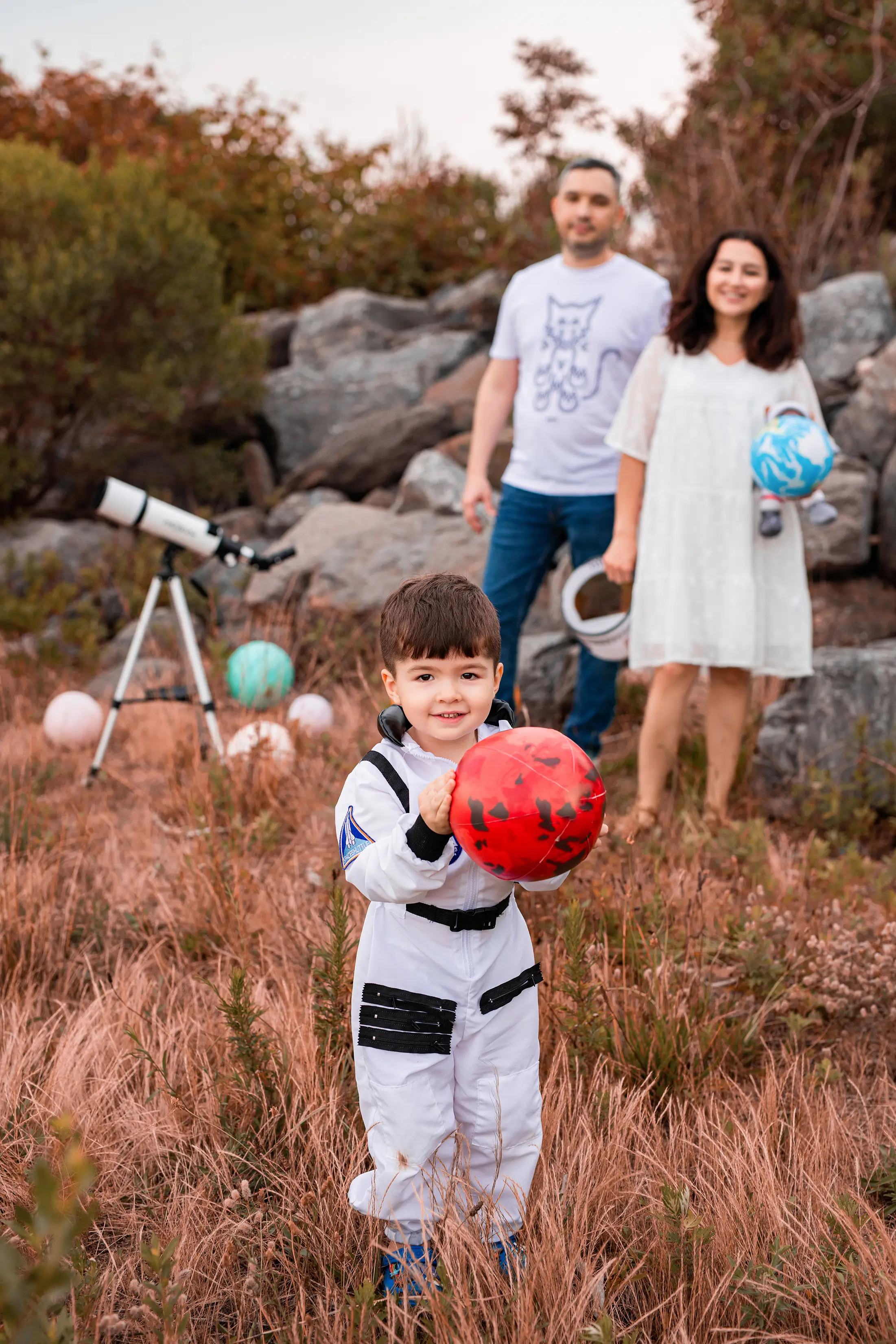 Child in an astronaut costume with parents during an outdoor family session