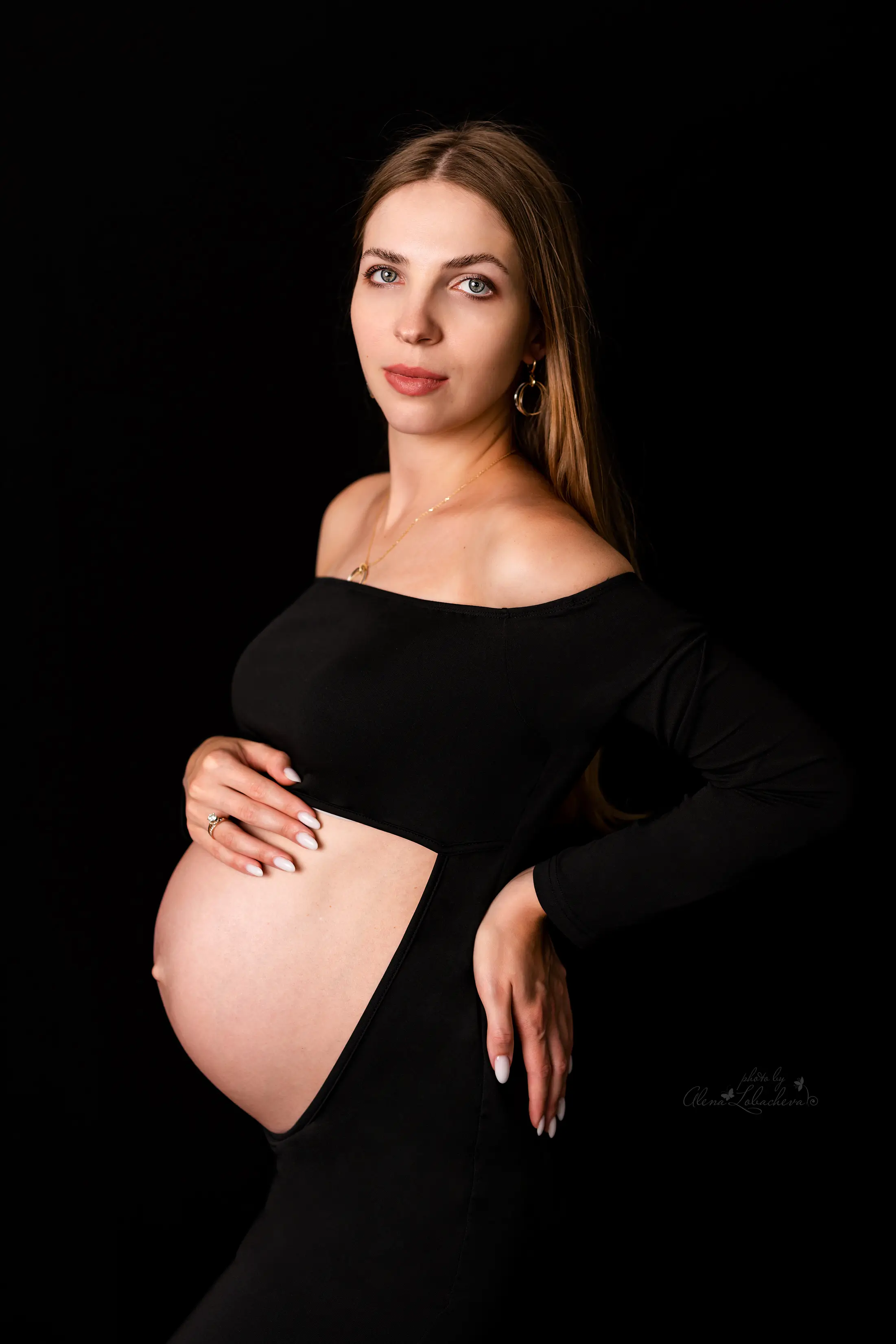 Expectant mother in a black cutout dress during a studio maternity session