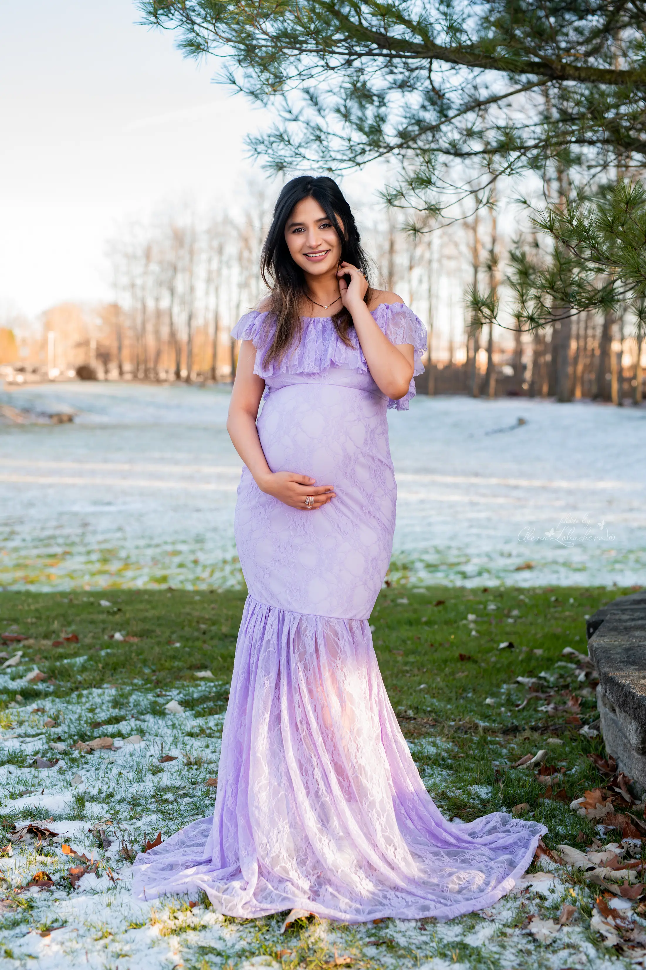 Pregnant woman wearing a purple lace gown for an outdoor winter maternity session
