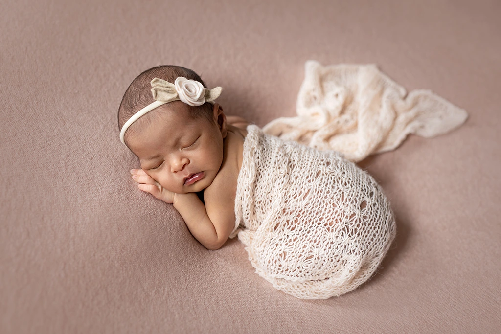 Sleeping newborn baby girl wrapped in cream knit fabric