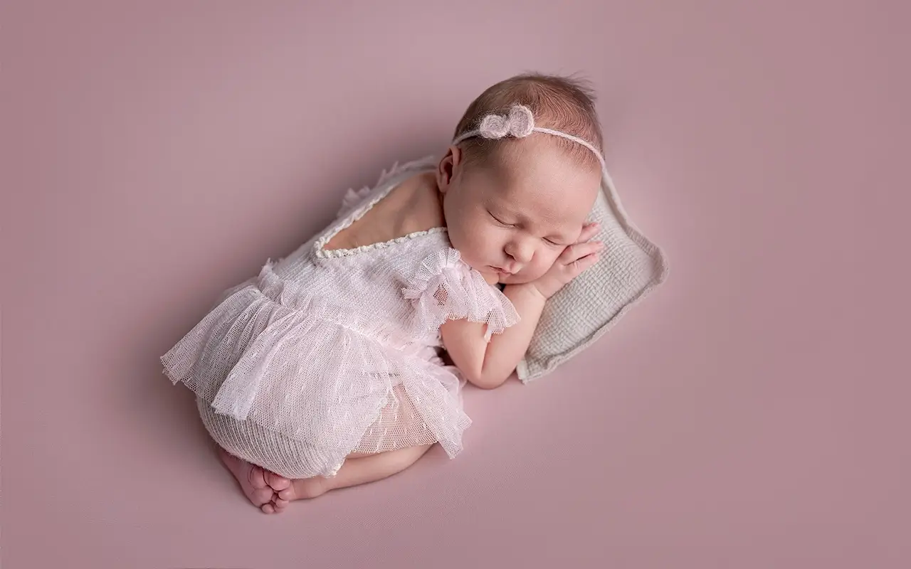 Sleeping newborn baby girl wearing a soft pink dress
