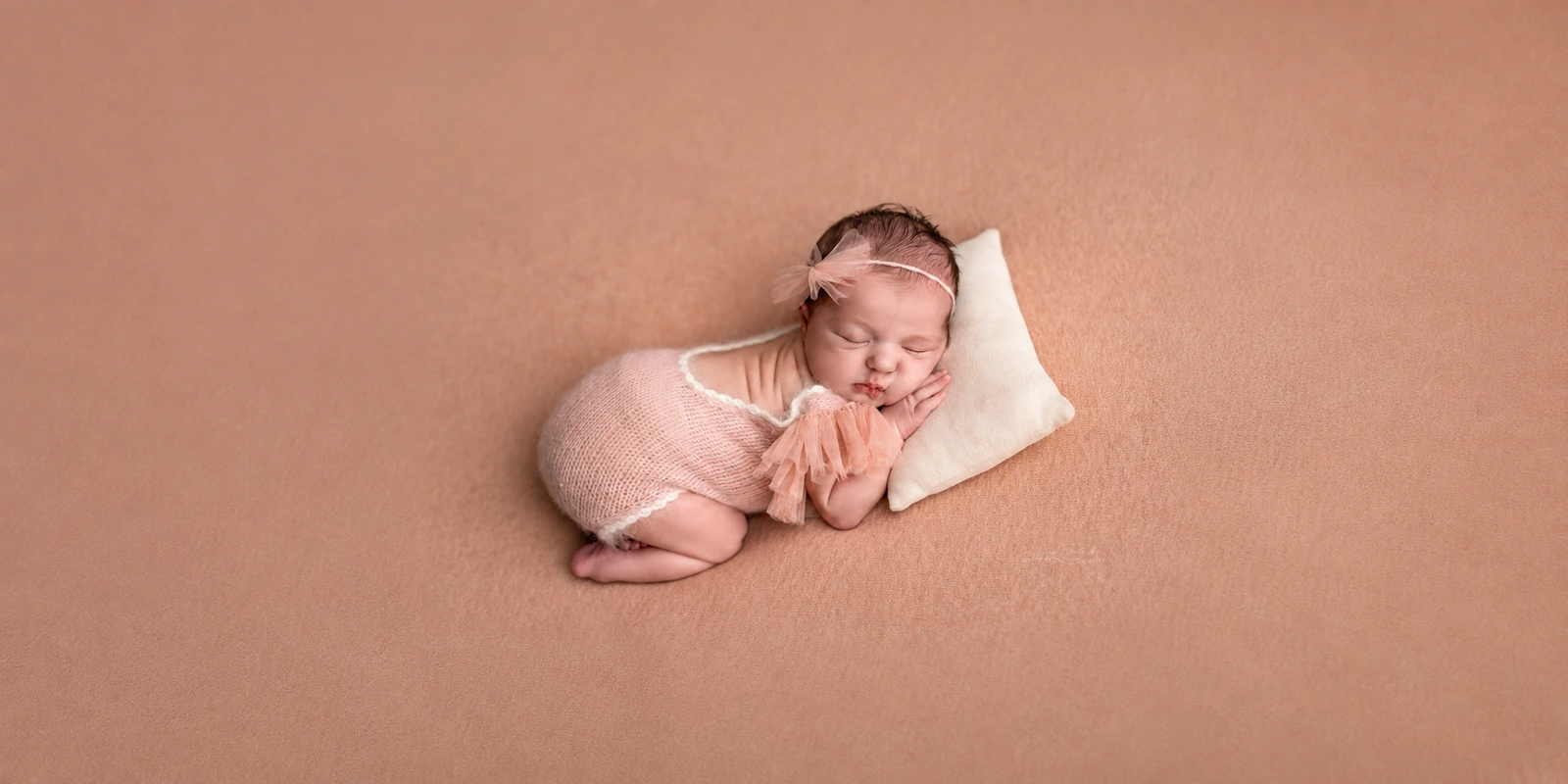 Sleeping newborn baby in soft pink wraps