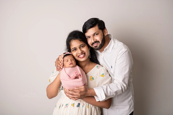 Mother and father holding their swaddled newborn during an in-home family portrait
